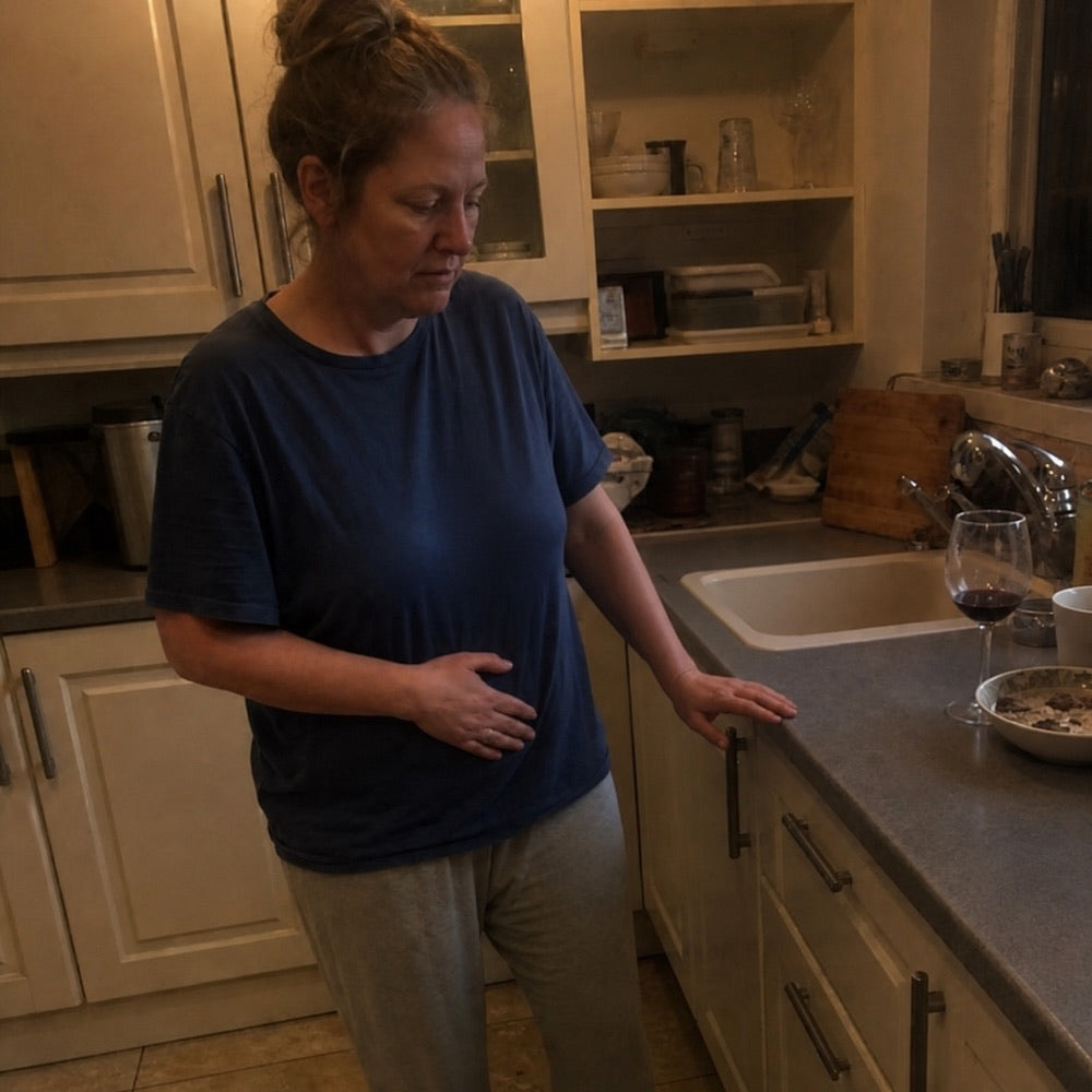 Woman noticing stomach discomfort after an evening drink