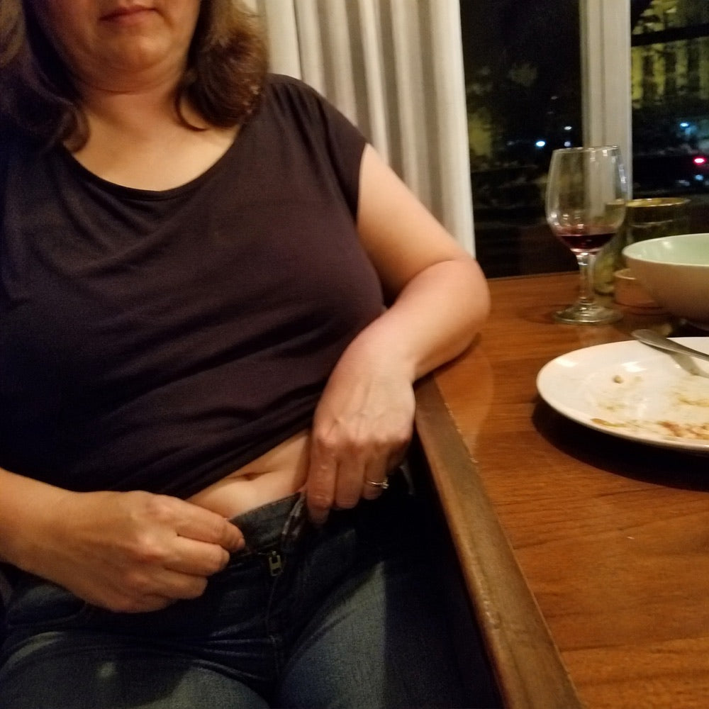 Woman adjusting a tight waistband after dinner